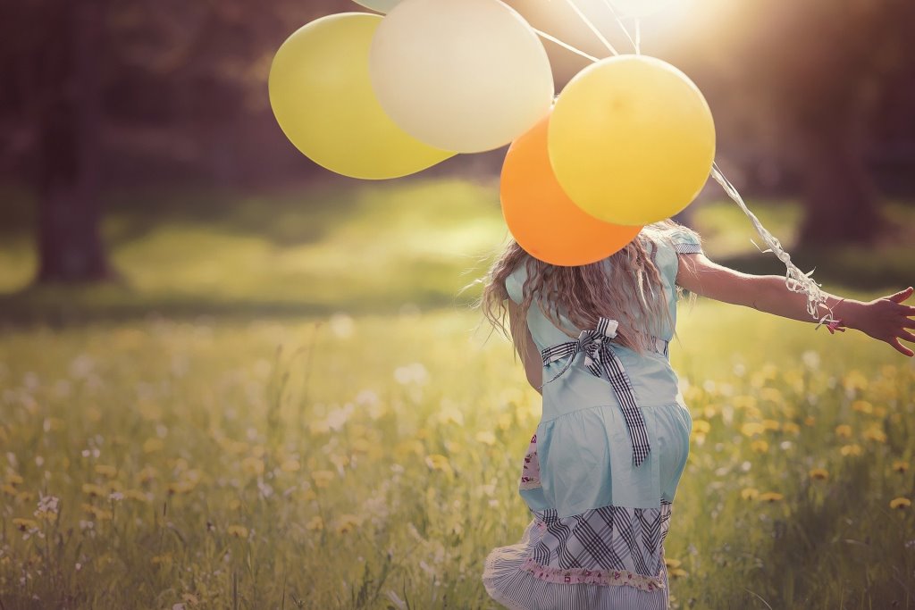 Mädchen rennt mit Luftballons