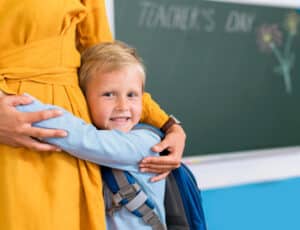 Schulstart mit Herz - Junge klammert zur Einschulung an Mama